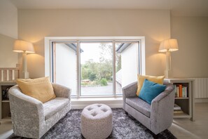 A living room with two armchairs, a round ottoman, and a bookshelf. - Luxury 5 Bedroom Home With Outdoor Jacuzzi and Indoor Sauna (Gorteanish)
