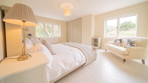 Une chambre à coucher avec un lit, une table de chevet, une lampe et un canapé blanc.