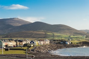 A coastal town with a prominent hill in the background, a rocky shoreline, and a row of colorful buildings. - Large House With Adjoining Cottage Close to Waterville (Waterville)
