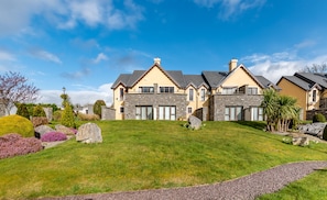 A large, two-story house with a stone facade and a well-maintained lawn. - 2 Bedroomed Home Just Steps From Kenmare Town (Kenmare)