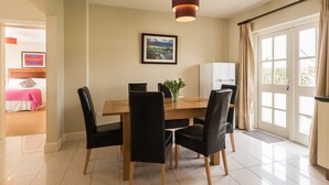 Een eethoek met een houten tafel, zwarte stoelen, een vaas met bloemen en een lijst met een foto aan de muur.