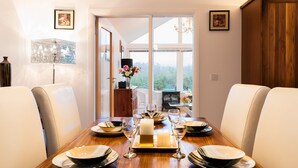 Un coin repas avec une table en bois dressée pour quatre personnes, entourée de chaises en cuir blanc.