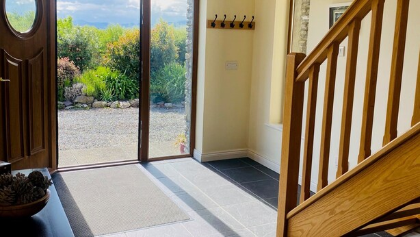 A spacious entryway with a wooden staircase, a glass door leading to a garden, and a tiled floor. - 3 Bedroom Home 15 Mins Drive From Kenmare Town (Dawros)