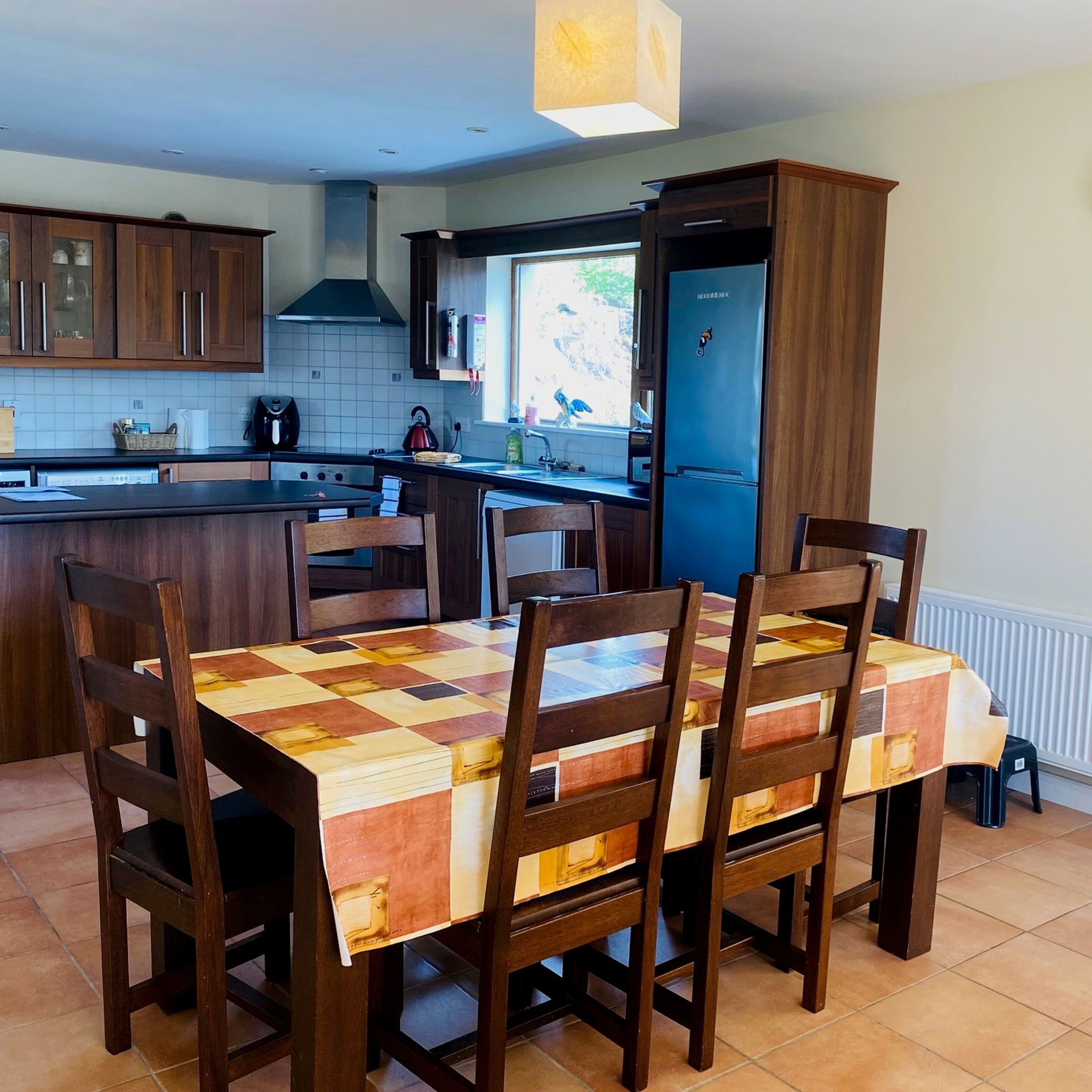 A kitchen with wooden cabinets, a tiled backsplash, a built-in oven, and a dining table with chairs.