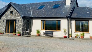 A modern house with a stone facade, large windows, and a sloped roof. - 3 Bedroom Home 15 Mins Drive From Kenmare Town (Dawros)