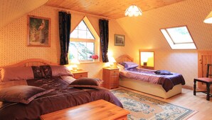 A cozy bedroom with two beds, a wooden ceiling, and a large window. - 3 bed Seaview Cottage (Dawros)