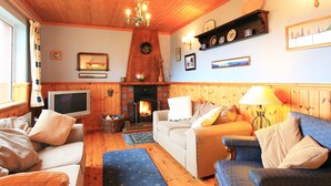 A cozy living room with wooden walls, a fireplace, a television, and comfortable seating. - 3 bed Seaview Cottage (Dawros)