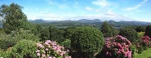 Ett landskap med berg, en sjö och en trädgård med rosa blommor.
