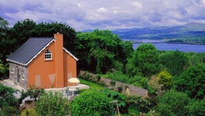 A house with a stone exterior, a tiled roof, and a small porch with a table and chairs. - 3 bed Seaview Cottage (Dawros)