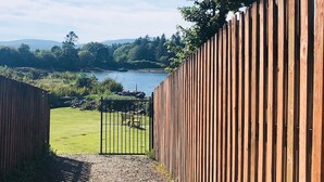 A wooden fence leading to a gate with a view of a lake and mountains in the background.