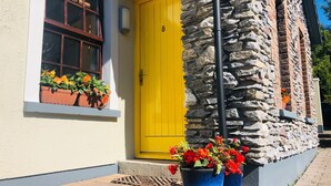 A building with a yellow door, stone walls, and flower pots on the windowsill.