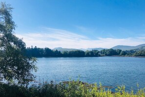 Un lac entouré d’arbres, avec des montagnes qui se dessinent à l’horizon.