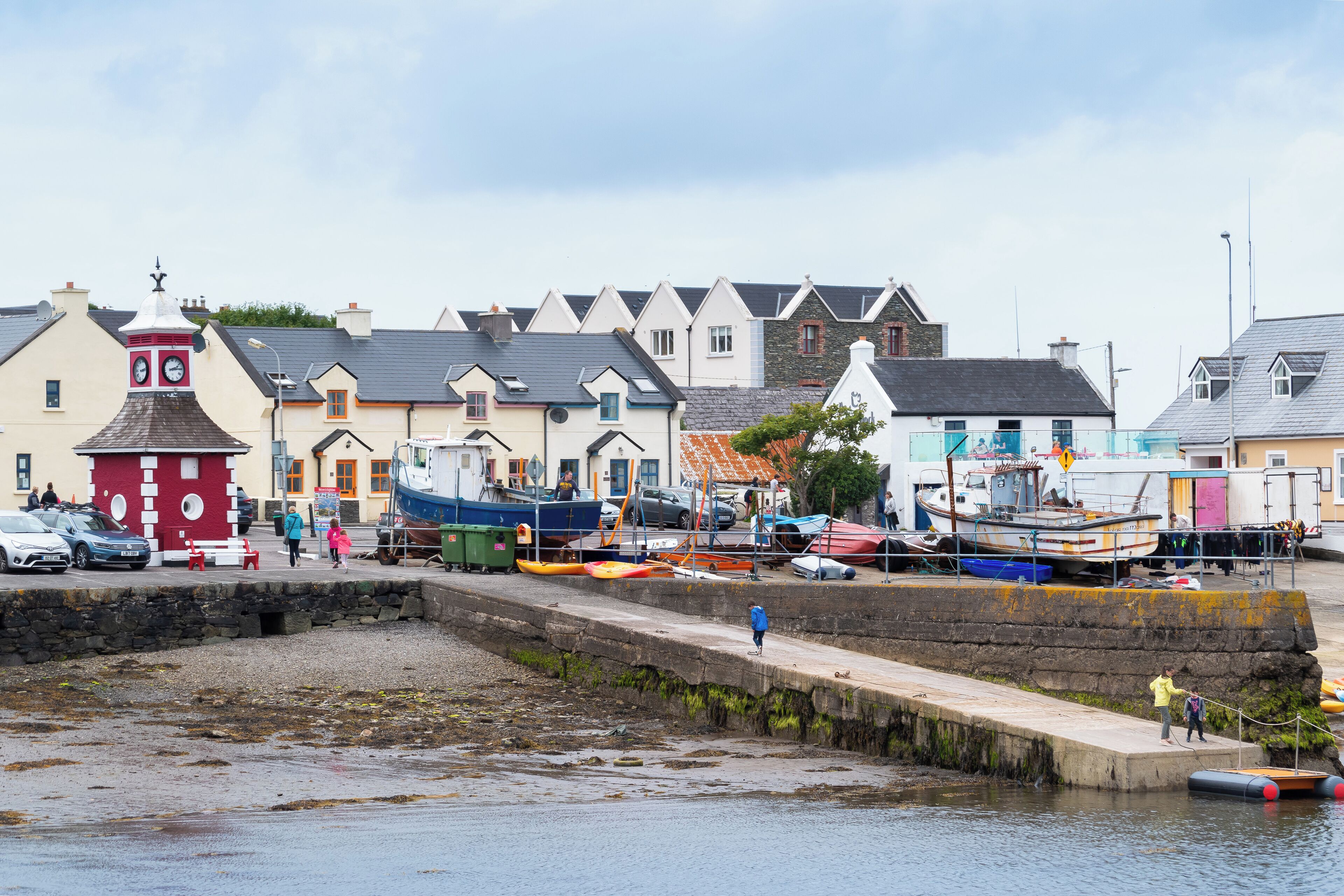 A coastal town with a stone pier, boats, and colorful buildings.