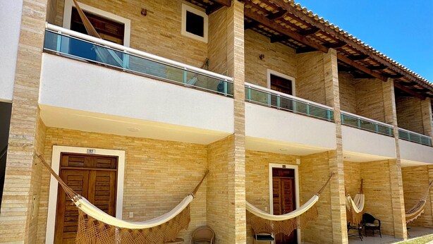 A two-story building with a balcony, hammocks, and outdoor seating. - Pousada Sandbeach (Trairi)