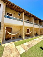 A two-story building with a balcony, hammocks, and outdoor seating.