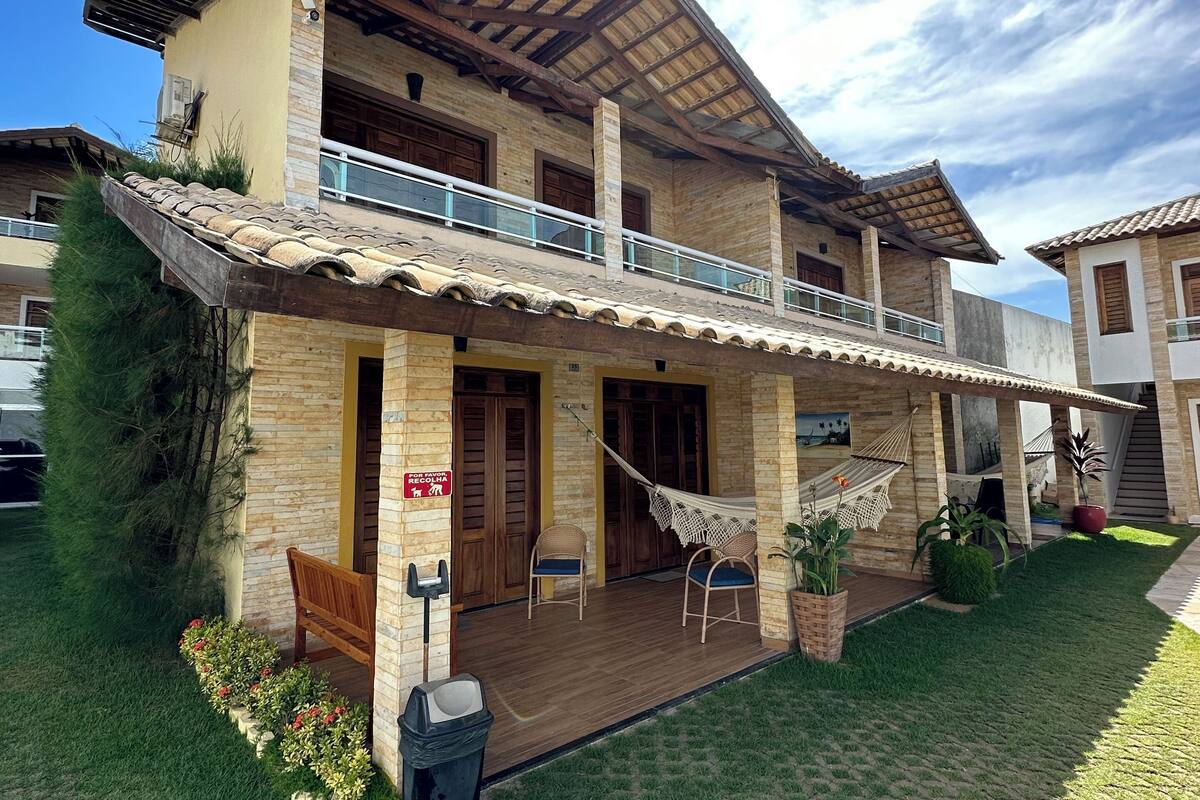 Ein zweistöckiges Haus mit Balkon, einer Holzterrasse und einem Rasen.