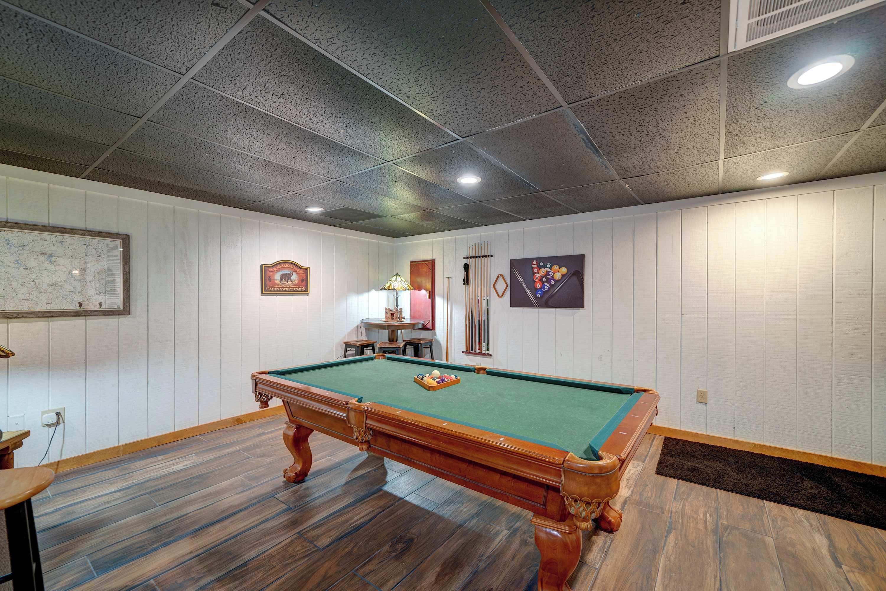 A pool table in a room with wooden flooring and white paneled walls.