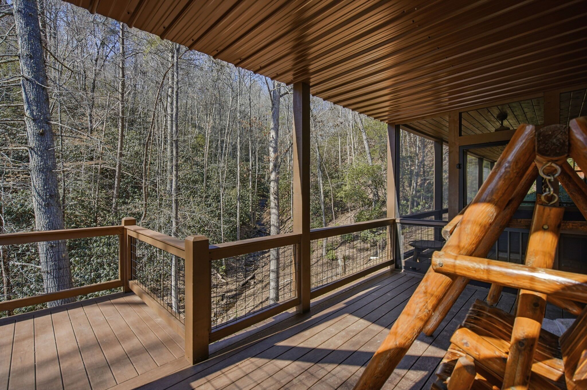 Eine Holzterrasse mit Geländer, mit Blick auf einen bewaldeten Bereich.