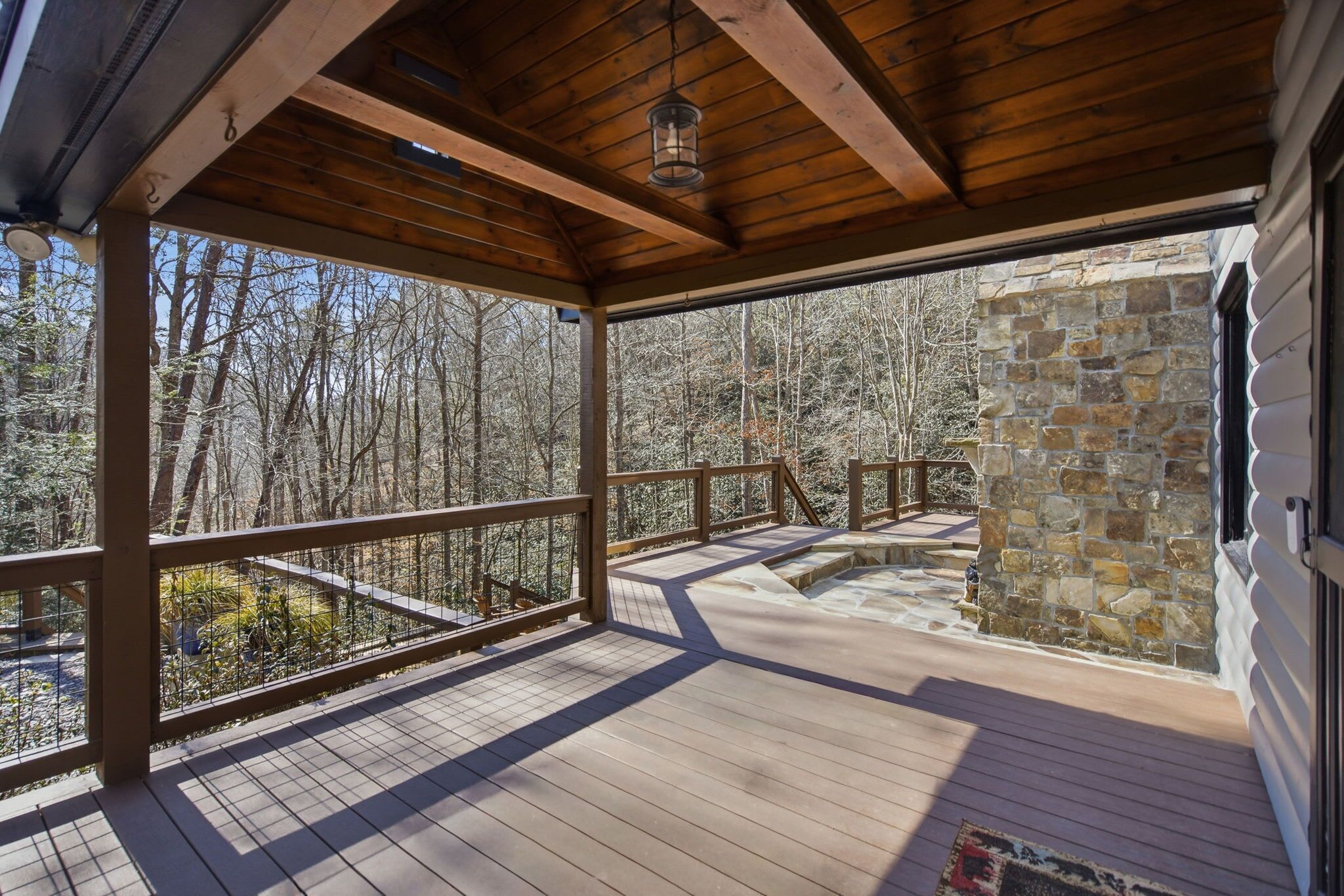 A wooden deck with a stone wall and a view of a forest.