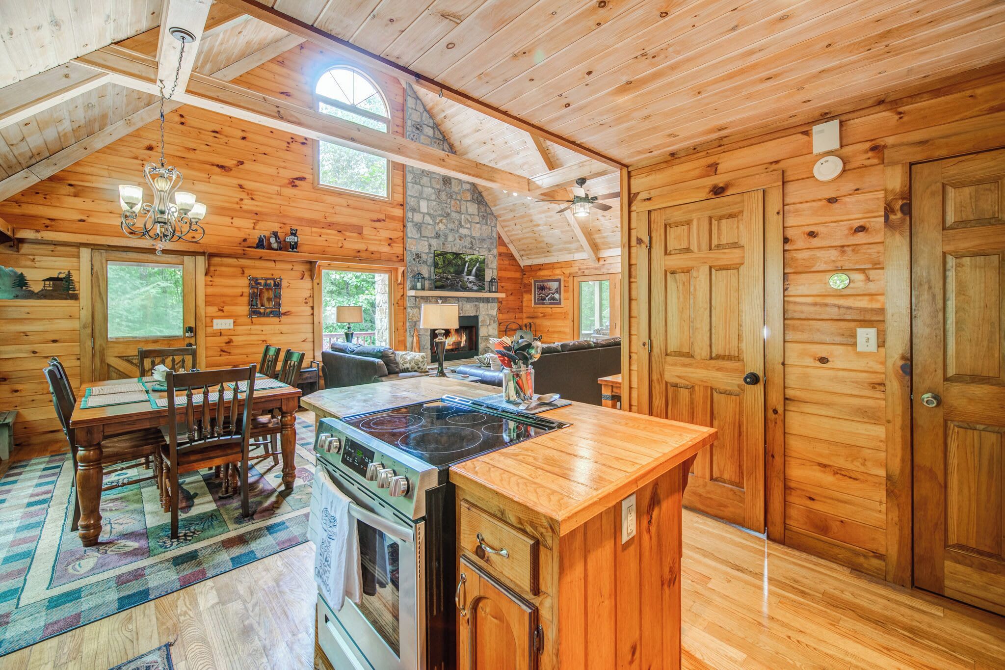 A rustic cabin interior with a dining area, kitchen, and living space.