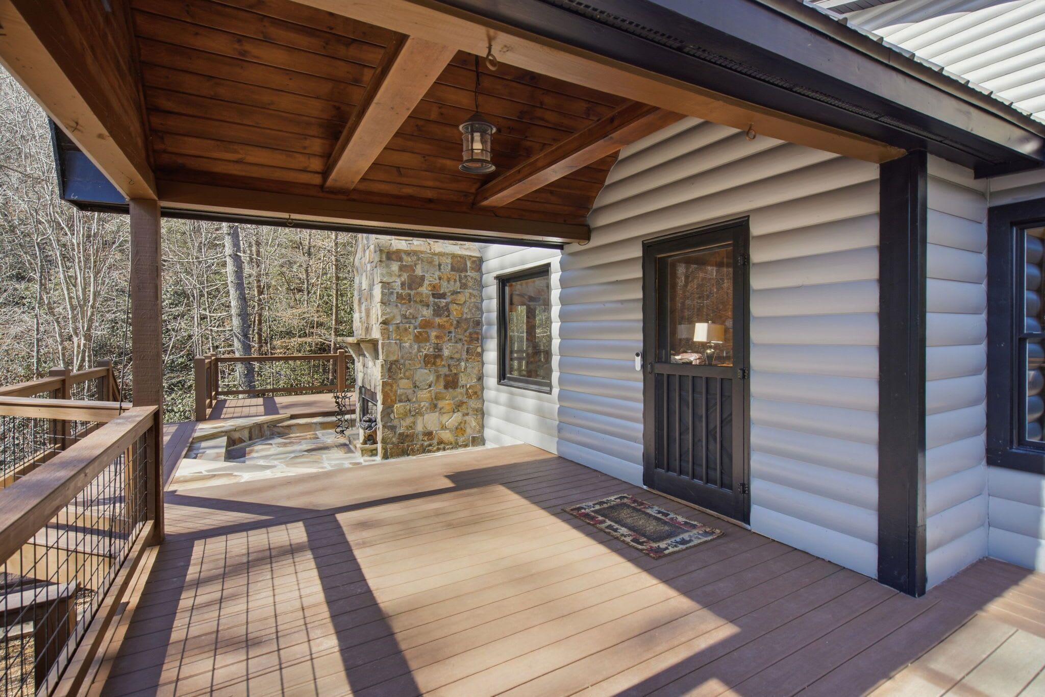 Un patio in legno coperto con un muro in pietra e una porta che dà su una cabina.