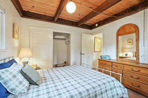 Ein Schlafzimmer mit Bett, Kommode und Spiegel.