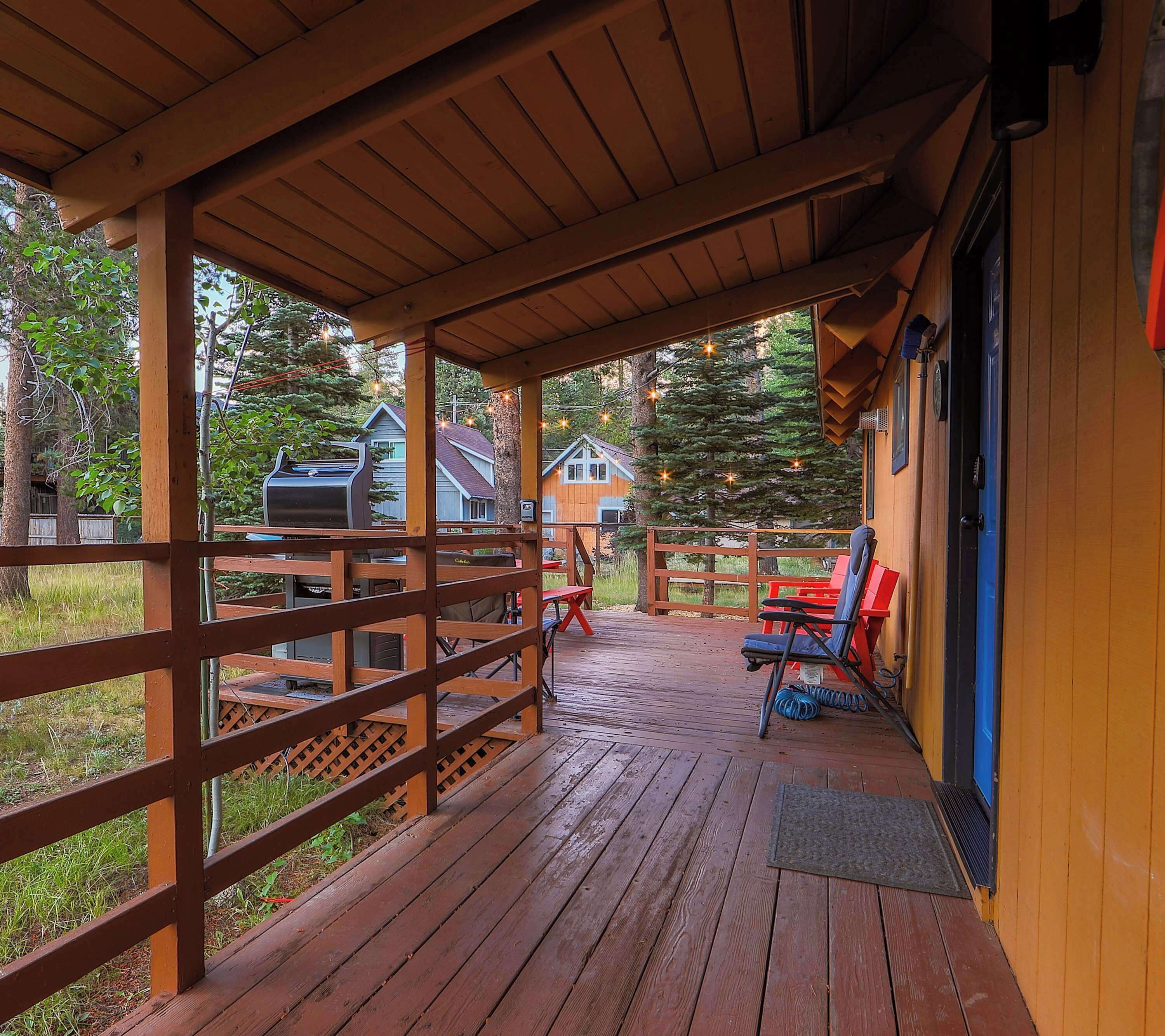 A wooden deck with a covered porch, outdoor seating, and a grill area.