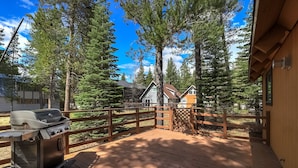 A wooden deck with a grill, surrounded by tall trees and a view of cabins. - Christmas Valley Chalet Tahoe Adventure Awaits! (South Lake Tahoe)