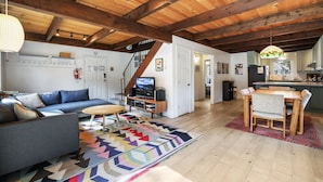 A spacious living area with a sofa, a coffee table, and a TV. There is a staircase leading to another room. - Christmas Valley Chalet Tahoe Adventure Awaits! (South Lake Tahoe)