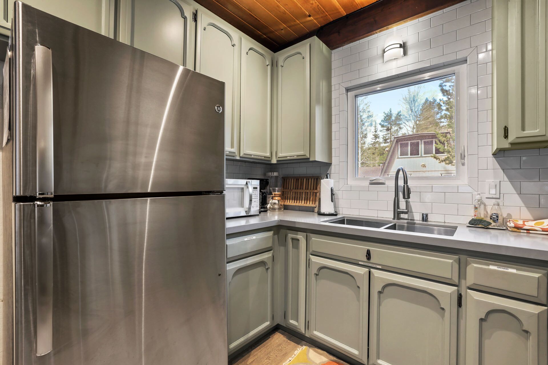 Una cocina moderna con electrodomésticos de acero inoxidable, armarios de tonos claros y ventana con vistas a un jardín.