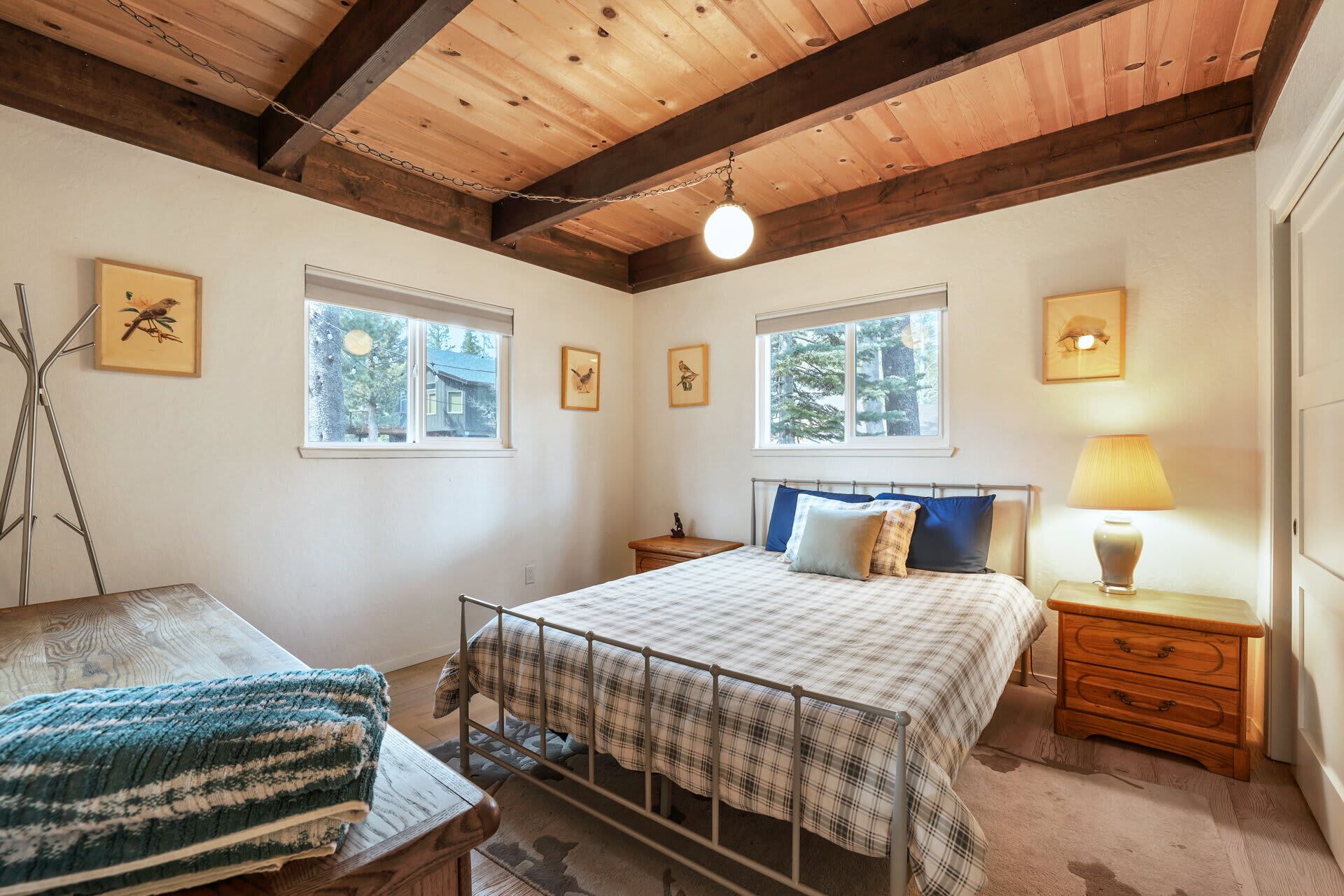 A bedroom with a bed, two bedside tables, a lamp, and framed pictures on the walls.