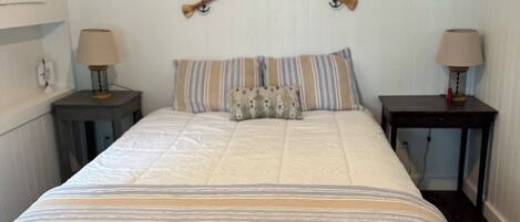 A bedroom with a bed, two nightstands, a wooden bench, and two lamps.