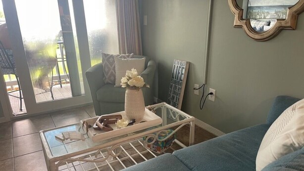 A living room with a blue sofa, a glass coffee table, and a white vase with flowers.