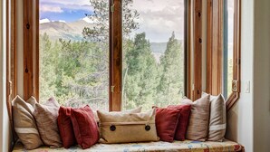 A window seat with a view of a forest and mountains. - Dogwood Retreat | 4BR Oasis with Hot Tub & Short walk to Main ST (Breckenridge)