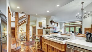 A spacious kitchen with wooden cabinetry, a large island, and a stainless steel dishwasher. - Dogwood Retreat | 4BR Oasis with Hot Tub & Short walk to Main ST (Breckenridge)