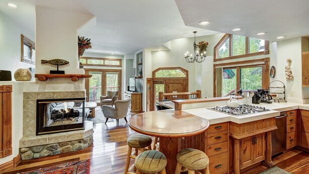 A spacious kitchen with a central island, wooden cabinets, and a fireplace. - Dogwood Retreat | 4BR Oasis with Hot Tub & Short walk to Main ST (Breckenridge)