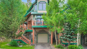 A multi-story house with a stone facade, a green roof, and a large front garage door. - Dogwood Retreat | 4BR Oasis with Hot Tub & Short walk to Main ST (Breckenridge)