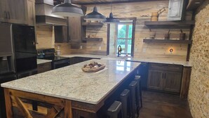 A kitchen with a large island, wooden cabinets, and pendant lighting. - Stay in the villa where the story's etched in stone  (Benton)