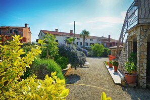A residential street with houses, a gravel path, and potted plants.