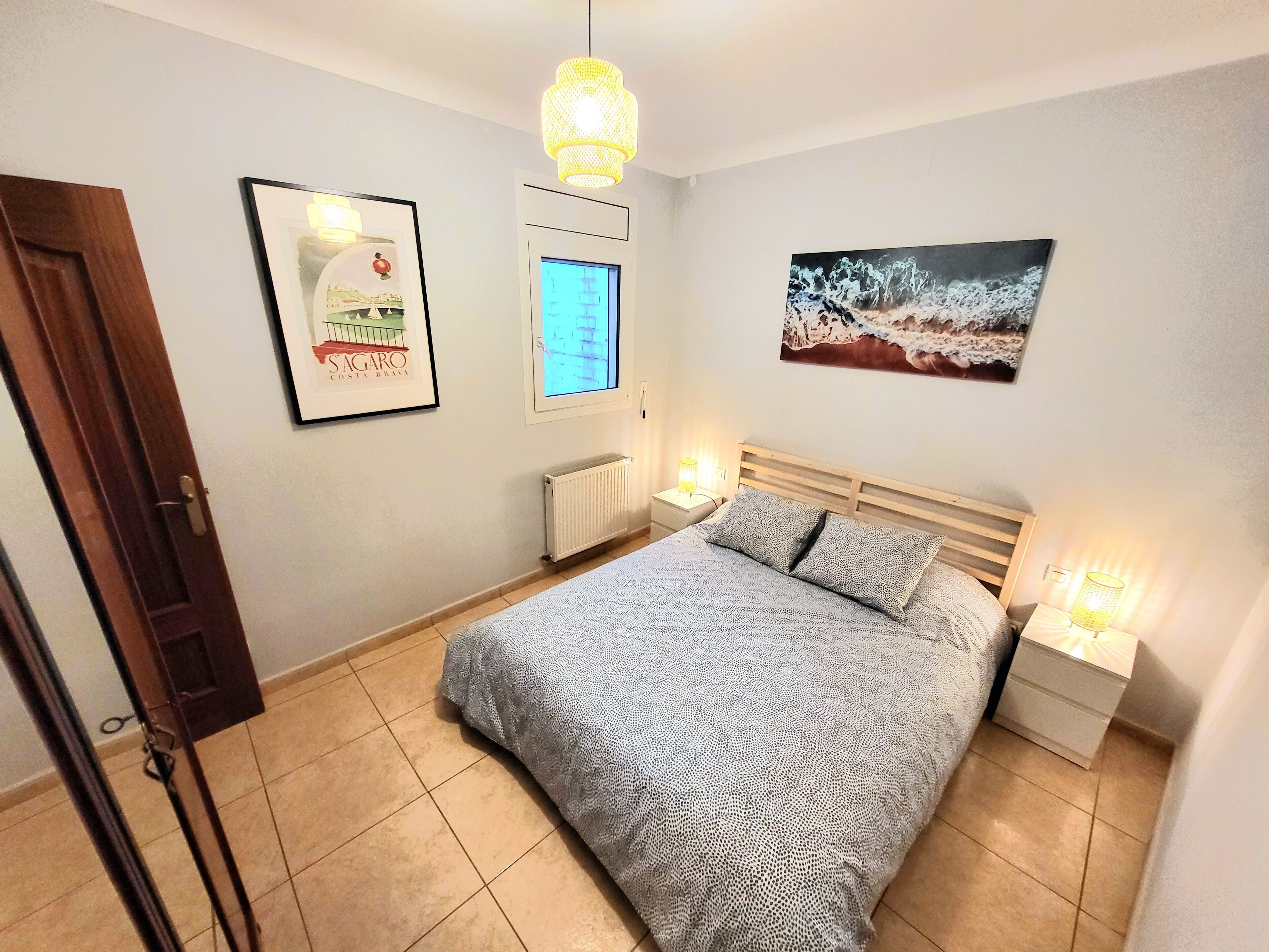 Une chambre à coucher comprenant un lit, une table de chevet, un téléviseur fixé au mur, un radiateur et une porte.