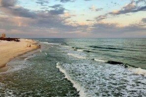 Una playa con olas y cielo nublado.