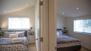 Une chambre avec deux lits, une fenêtre et une porte.