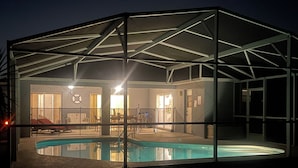 Ein überdachter Pool mit Glasverkleidung, ein Whirlpool und eine Terrassenanlage mit Gartenmöbeln.