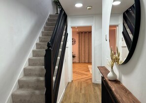 Staircase leads to an upper floor, flanked by walls and a wooden floor.