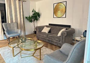 Relax in this stylish living room with a sofa, armchair, and coffee table, surrounded by a large potted plant.