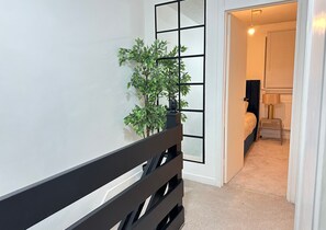 Enter a serene bedroom with a neatly made bed and a bedside table featuring a lamp.
