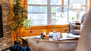 A cozy room with a wooden bench, a table with a chessboard, candles, and a potted plant.