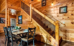 Un interior de madera con una escalera, una mesa de comedor y sillas.