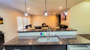 A kitchen with granite countertops, a double sink, and pendant lighting. - Home In The Heart Of Alvin! (Alvin)