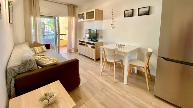 Un espace de vie compact comprenant un canapé, une table à manger, des chaises, un téléviseur et un réfrigérateur.